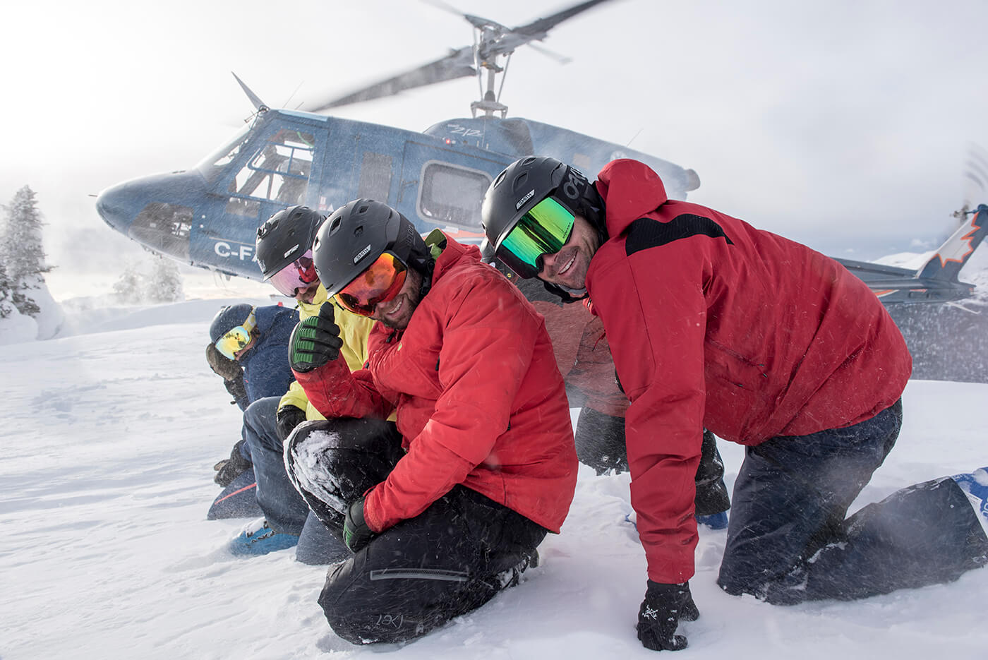 group in front of helicopter taking off for heli skiing bc